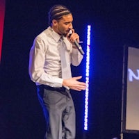 a man in a suit and tie speaking into a microphone